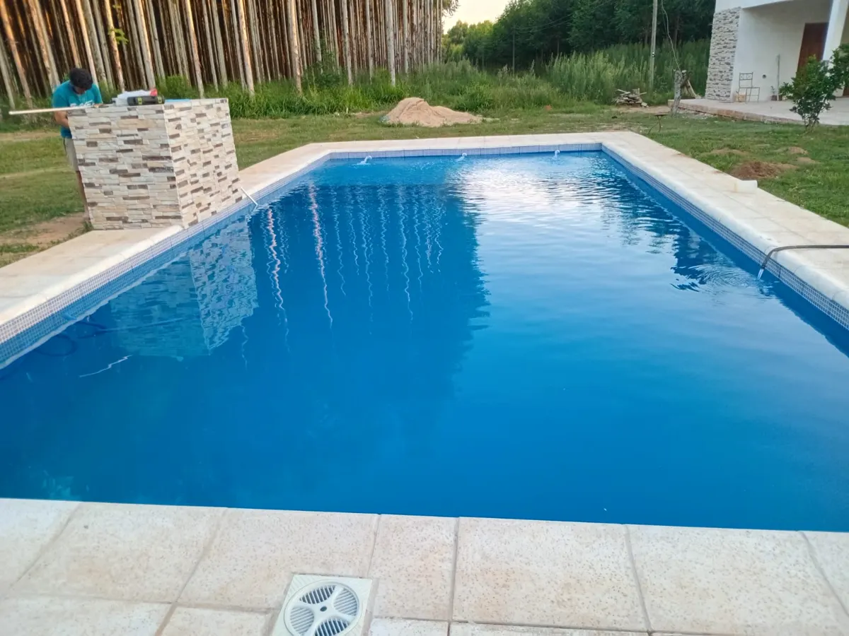 Piscina terminada por Piscinas San Antonio con borde claro y cascada de piedra
